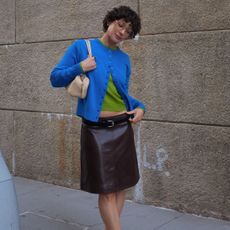 a woman wearing a blue cardigan and leather skirt