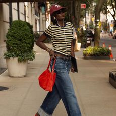 woman wearing striped shirt styled with a baseball hat and jeans