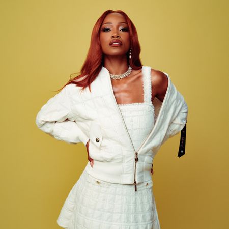 Promo image for Keke Palmer's July Who What Wear cover story. She is wearing a white matching jacket, top, and skirt set by Chanel with a diamond and pearl necklace. 