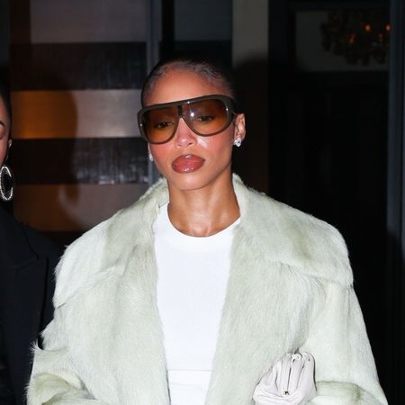 Lori Harvey wearing a coat, white t-shirt, plaid pants, and pointed toe heels