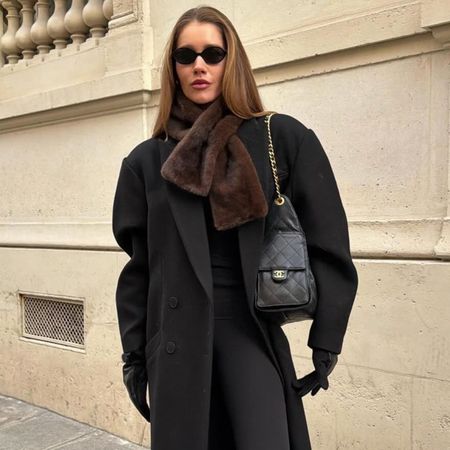 Woman in a black overcoat and brown faux-fur scarf