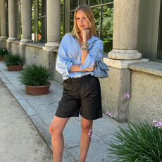 Woman wearing blue button-down shirt, black shorts, and colorful jewelry in Madrid.